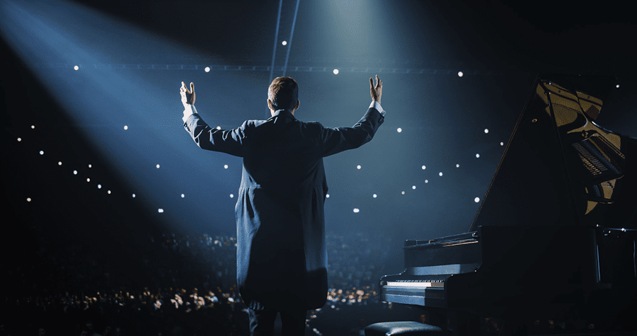 Concert pianist acknowledging audience under spotlight.